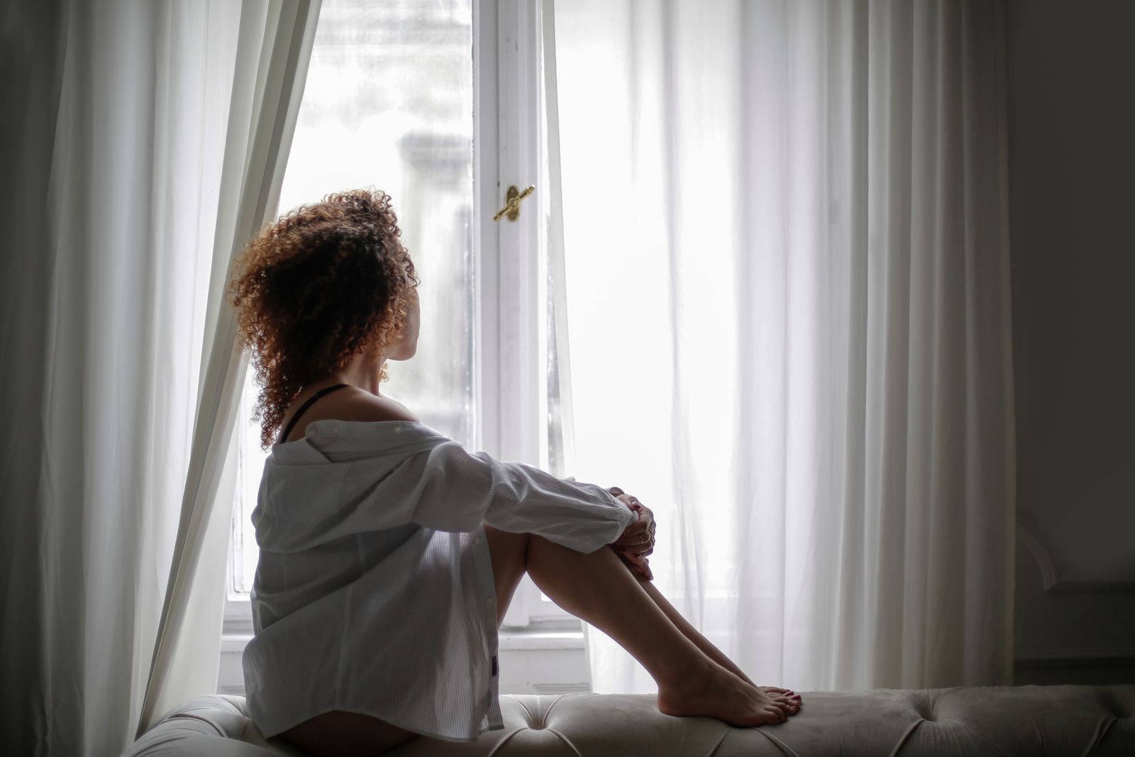 A woman sitting quietly in soft light by a bright window